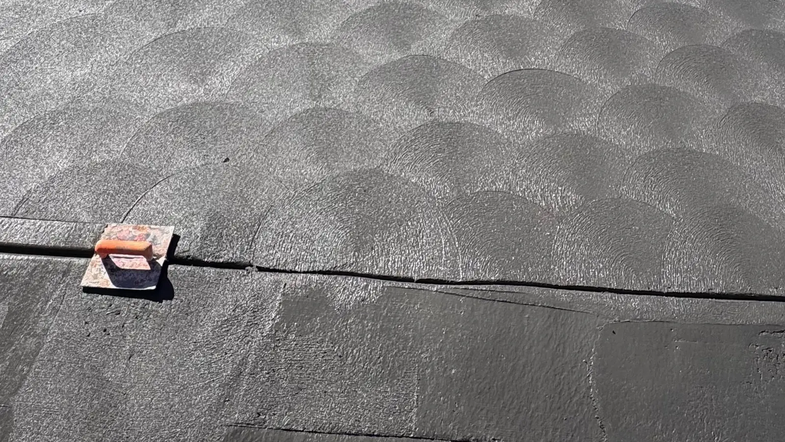 Close view of a fresh scallop-patterned concrete driveway surface with a small finishing float