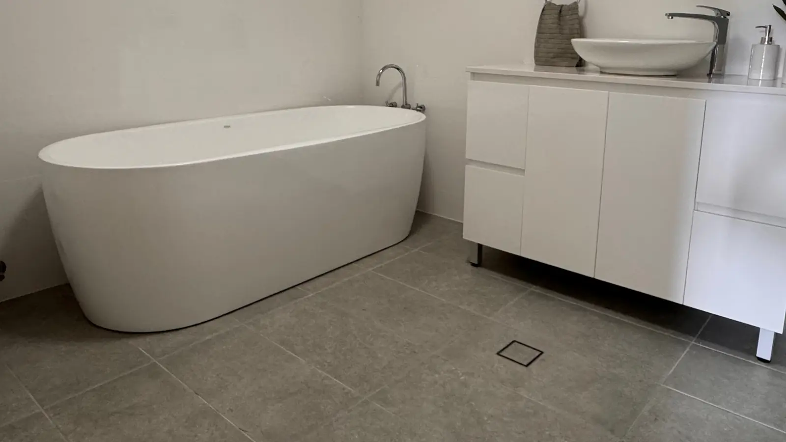 Completed bathroom with freestanding bath, vanity, basin and tiled floor